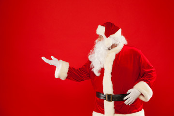 Santa Claus pointing in blank a place, red background