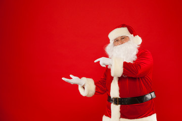 Santa Claus pointing in blank a place, red background