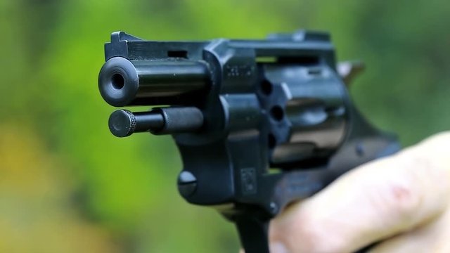 Man shoots a revolver. Soldier shoots a pistol. Man cocks and shoots. Man with black gun, raise the cock, cock the gun, close up
