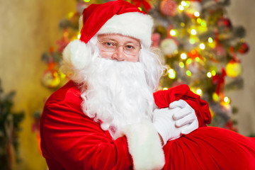 Santa Claus with giftbox on background of sparkling firtree