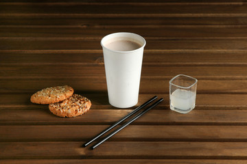 Coffee in a white cup, cookies are close, on a light wooden table