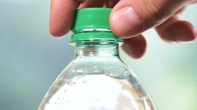 Hands opening a bottle of fresh mineral water fullHD video. Close-up of plastic bottle cool soda water on abstract light background. 