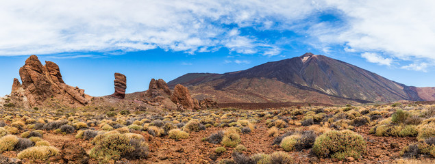 Panoramic view of unique Roque Cinchado unique rock formation with famous Pico del Teide mountain volcano summit in the background on a sunny day, Teide National Park, Tenerife, Canary Islands, Spain