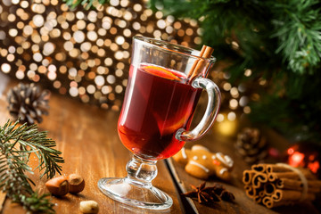 Fototapeta na wymiar Winter holiday hot alcohol drink. Mulled wine with fruits and spices by Christmas tree.