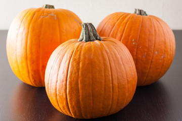 Three ripe pumpkins on a dark wooden surface