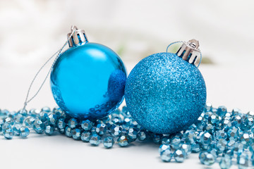 Two blue ornaments ball with tinsel on white table - 125653908