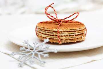 Tied wafers with caramel on white plate and decorative snowflake