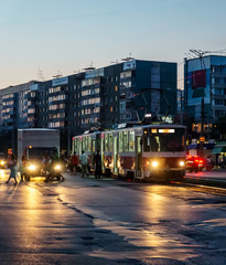 tram, car, dusk, city, people, headlights, dark house in the background