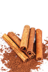 Group of cinnamon sticks on cacao powder, isolated on white background.