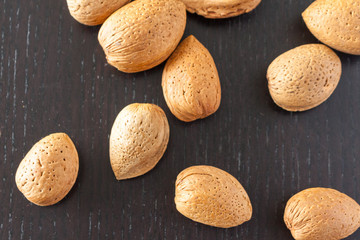 Overhead view of almonds in the shell on a dark wooden surface
