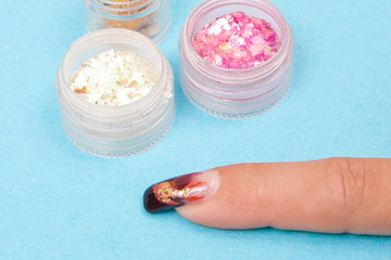 Manicure. Master make Art nail design. Finger closeup on a blue background. 
