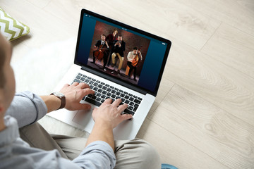 Man watching musical performance online on laptop. Video call and chat concept.