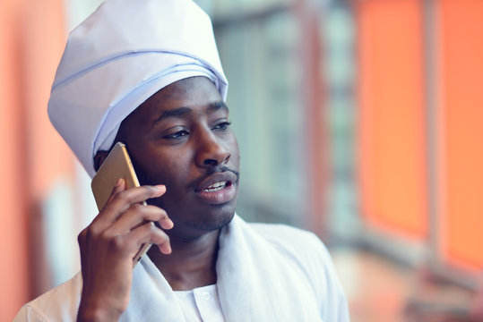 Sudanese Business Man In Traditional Outfit Using Mobile Phone In Office