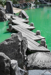 Obsolete elegant wooden bridge across a vivid pond