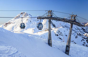 Fototapeta na wymiar Cableway lifts on snowy mountains background beautiful winter scenic landscape