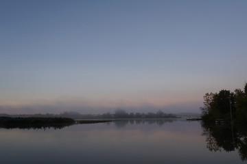 Obraz na płótnie Canvas Fog over calm river on cold October morning