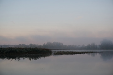 Fototapeta na wymiar Fog over calm river on cold October morning