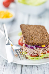 Wooden table with Tuna sandwich (on wholemeal bread; selective f