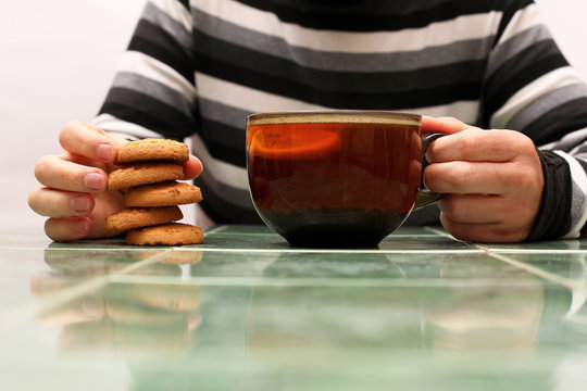 hands of a man with a cup of tea and biscuits