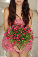 Pretty girl sitting with a bouquet of flowers in pink floral dre
