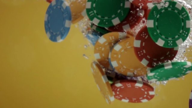 Casino poker chips falling in water close up in slow motion.
