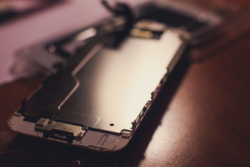 A close-up process of disassemble and dismantle modern mobile phone smartphone with broken shattered display glass and changing details at home