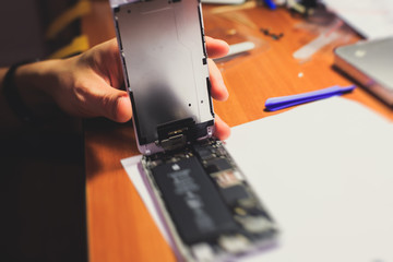A close-up process of disassemble and dismantle modern mobile phone smartphone with broken shattered display glass and changing details at home