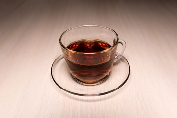 glass cup with tea on a saucer placed on a table