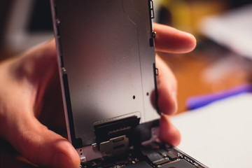 A close-up process of disassemble and dismantle modern mobile phone smartphone with broken shattered display glass and changing details at home