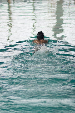 swimmer swimming in pool, rear view.