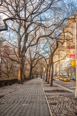 Empty Fifth Avenue sidewalk along Central Park in New York City on clear winter day