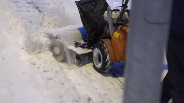 Man working with snow blowing machine on pavement after snow fall in winter. 4K