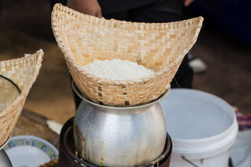 Sticky rice steam cooking process with water boil pot and bamboo basket.