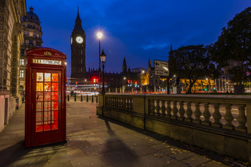 Naklejka na ściany i meble Famous English red telephone boxes with Big Ben in London at night, England, UK