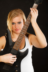 Obraz premium Blonde woman holding electric guitar, black background