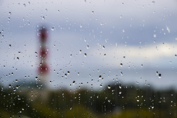 Lighthouse on the sea for wet glass with raindrops