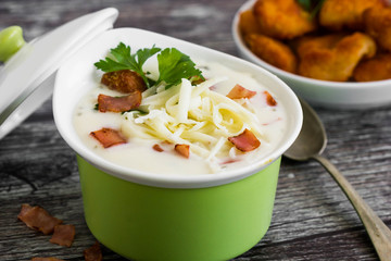 Hot soup in green bowl with ham and cheese on top.
