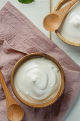 Yogurt in wooden bowl on wooden background with pink cotton and