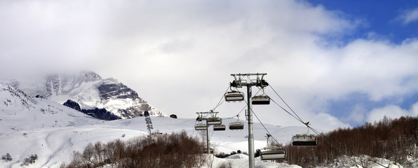 Panoramic view on chair lift on ski resort and snow mountain in