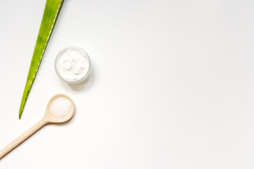 cream, aloe and wooden spoon on white backround top view
