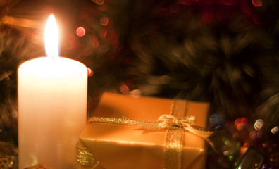 Christmas and New Year`s  evening burning candle and  gold present boxes wrapped in  paper with bows of gold and silver ribbons. Retro style greeting card yellow toned background with holiday tinsel.