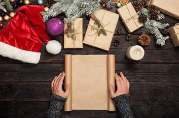 Mens hands holding blank sheet of paper with Christmas gifts