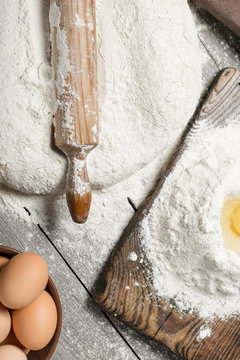 Rolling pin with flour and eggs close up, top view