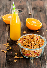 flakes in bowl with orange on dark wooden background