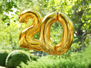 Golden birthday balloons on green background