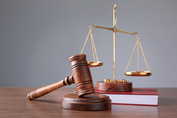Judge's gavel with book and justice scales on wooden table and grey background