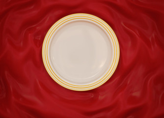 Empty round glazed plate with simple shiny frame on folded silk cloth.
