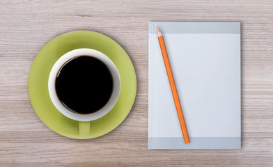 Green coffee cup, note book, on wooden table