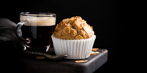 Delicious homemade coconut cinnamon muffin with almond flakes on black background. Healthy food concept with copy space.