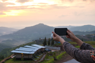 Young woman take photo of mountain view by smart phone in morning.